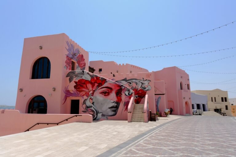 Vibrant street art mural on a pink building facade in Doha's Katara Cultural Village, showcasing contemporary art.