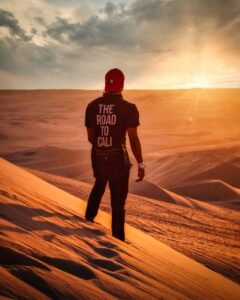 Man standing on sand dunes in Huacachina Desert, Peru at sunset, embracing solitude and adventure.